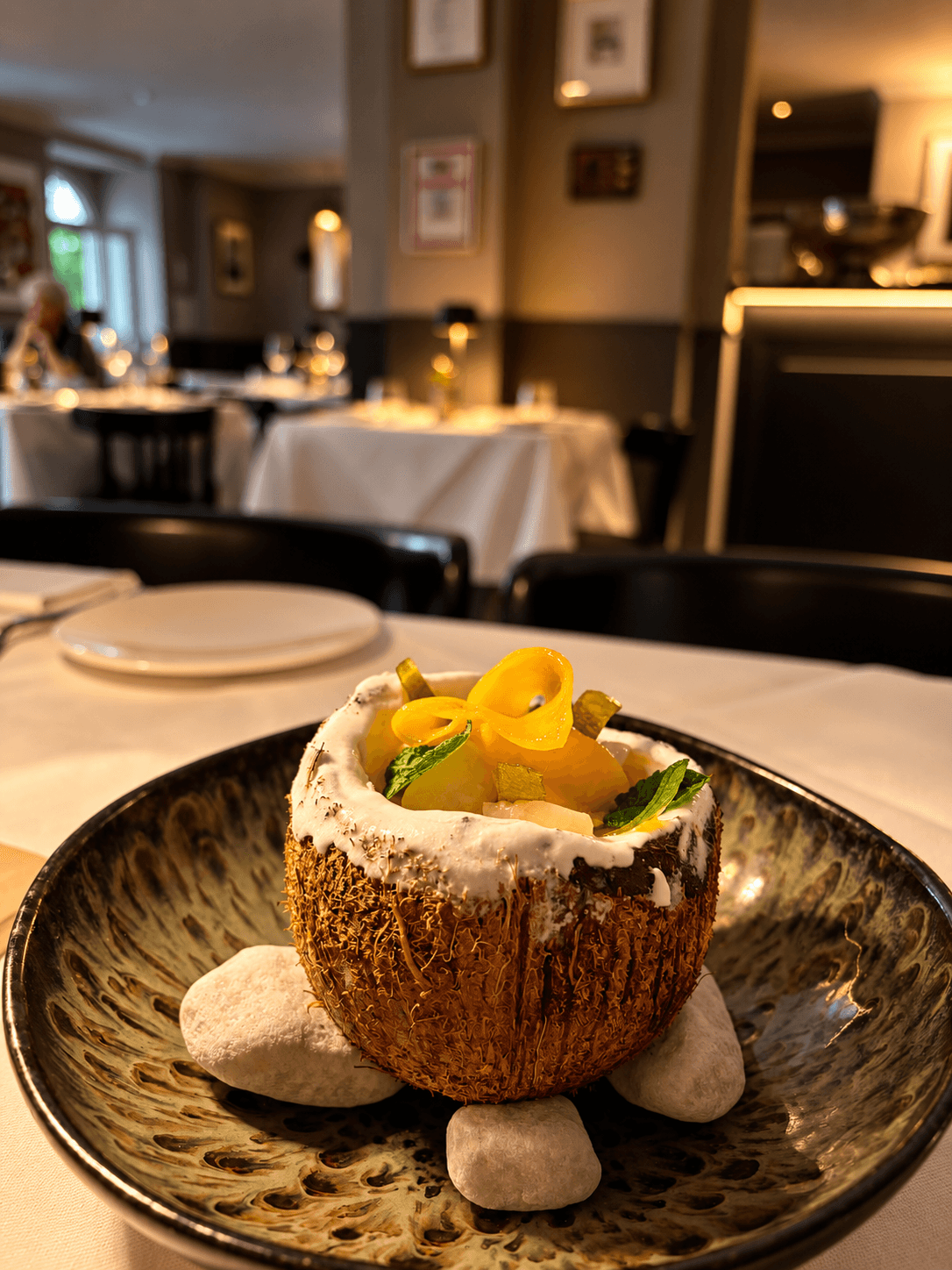 Dessert served in a coconut, on stoneware with white stones