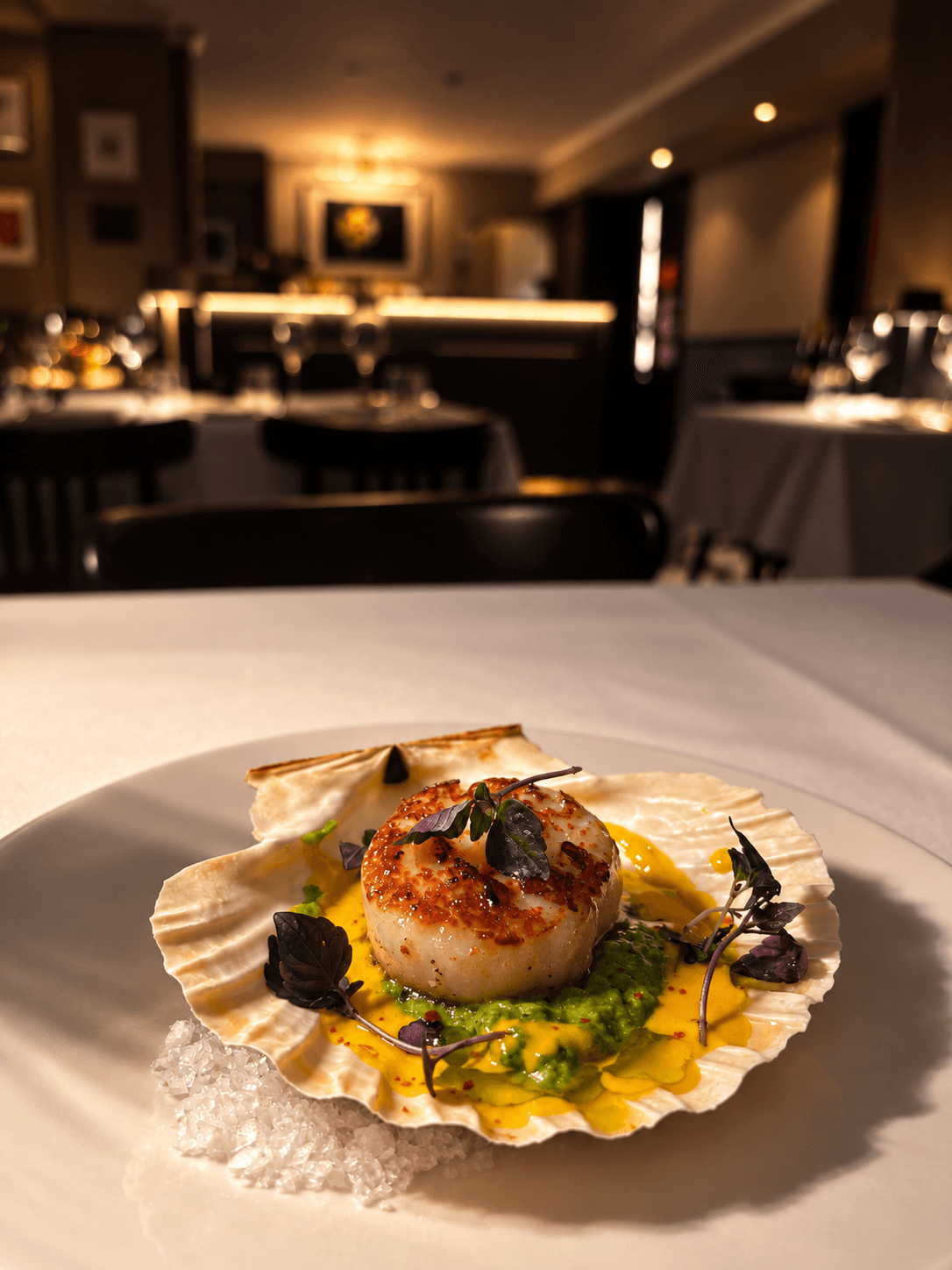 Scallop on the shell with yellow sauce and herbs