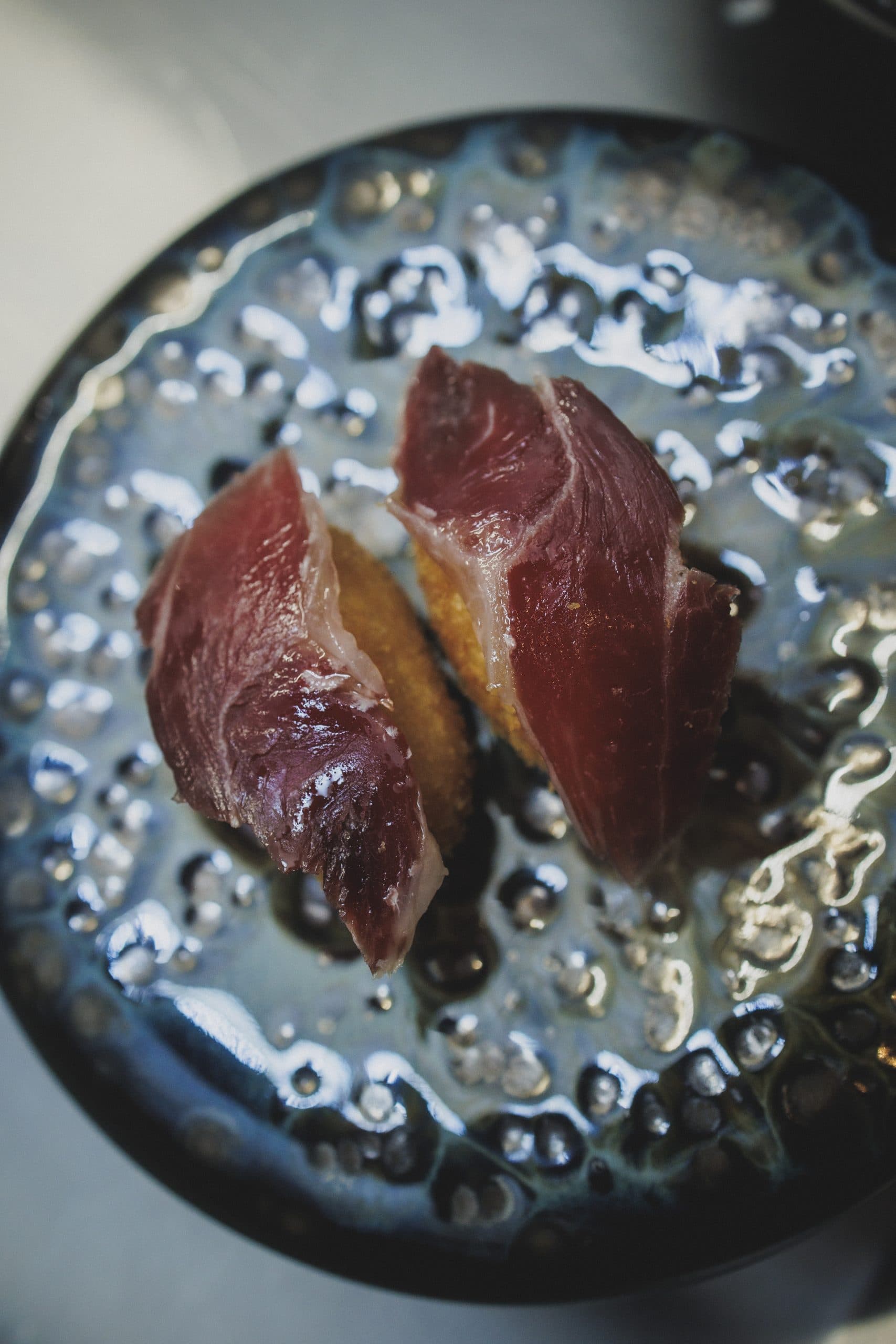 Croquetas doradas con jamón ibérico sobre cerámica de esmalte azul