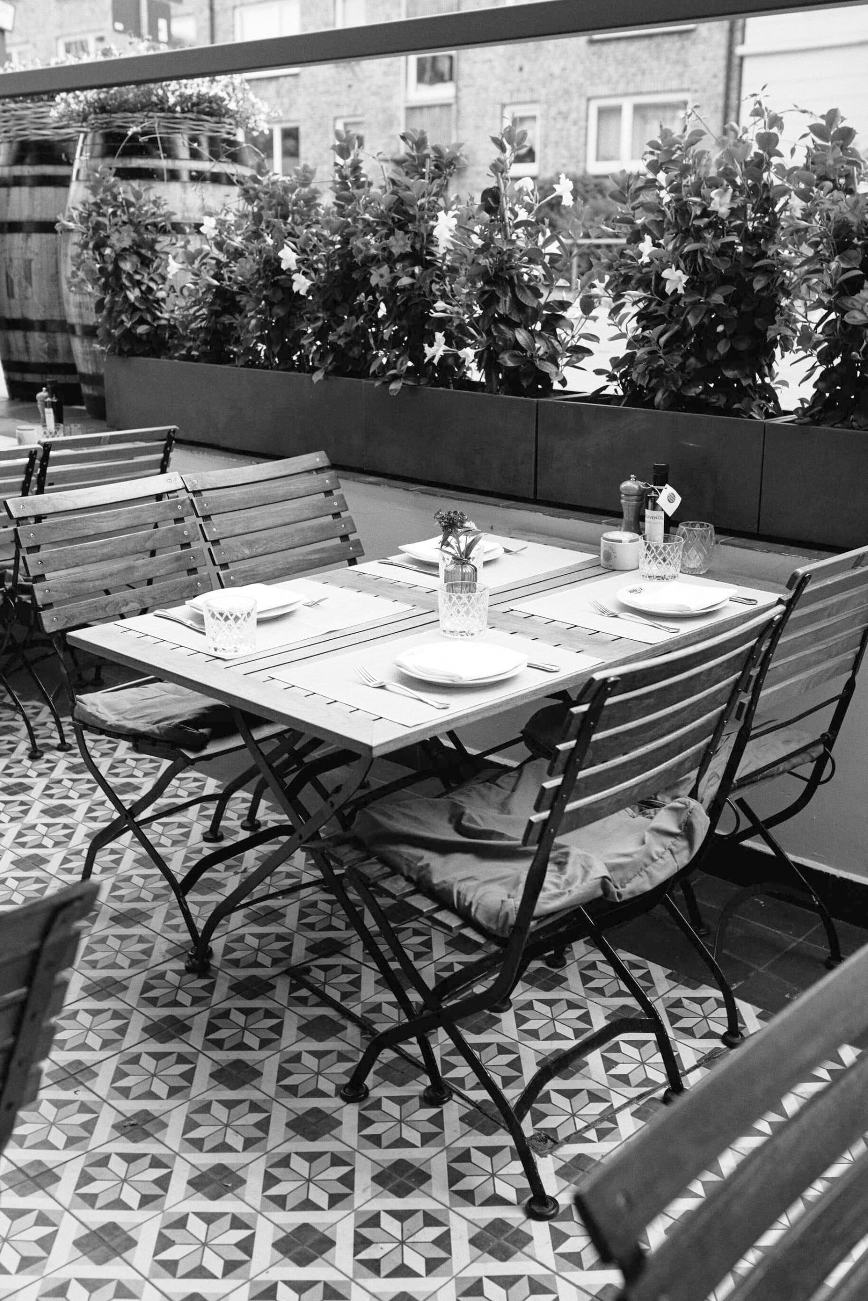 Nanai terrace in Winterhude with a set table, chairs and flower boxes